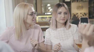 Bir kafede iki kız arkadaşım: bir smarftone bir şey için arıyor.