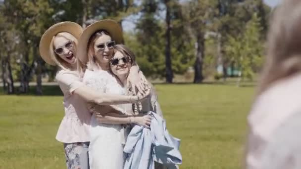 Três jovens mulheres em óculos de sol abraçam, se divertem e são fotografadas — Vídeo de Stock
