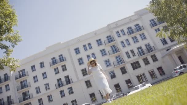 Mujer con sombrero en el fondo de un edificio moderno con una fachada blanca , — Vídeos de Stock