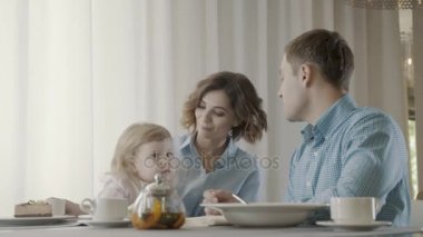 Kızı onun anne kucağına oturur. Bir çocukla mutlu aile