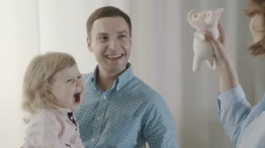 Anne ile yumuşak oyuncak oynuyor, kız sevinçle çığlık atıyor ve sevinir.