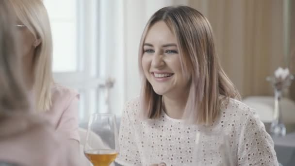 Deux femmes similaires communiquent avec des amis dans un café et sourient — Video