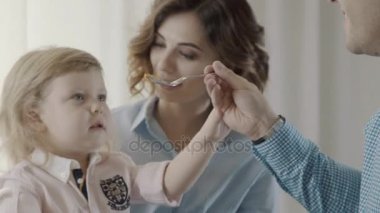 Küçük sarışın kız onun anne kucağına oturmuş, yanlarında bir babadır