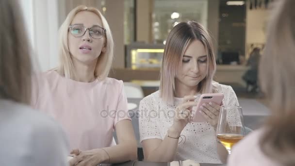 Gezelschap van vrienden in een café en show foto's op de telefoon en lach. — Stockvideo