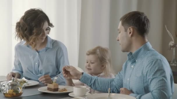 Menina agradável de três anos com em um café, os pais dão uma refeição — Vídeo de Stock