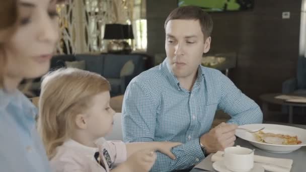 Os pais são tocados por sua filha, que tenta comer sozinha . — Vídeo de Stock