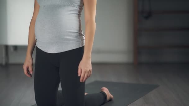 En vacker gravid kvinna sträcker sig i en yogastudio. — Stockvideo