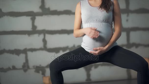 Gyönyörű fiatal terhes asszony hasát simogatta.