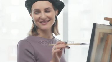 Kadın bir fırça tutan ve çizim, gülen sanatçı bir bere içinde.