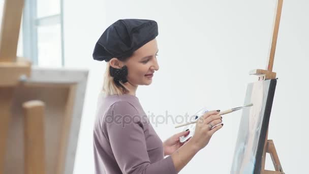Eine inspirierte Frau mit Baskenmütze in einem hellen Atelier — Stockvideo