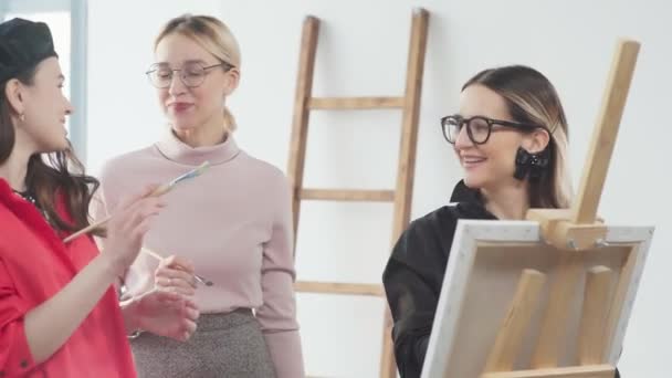 Las artistas femeninas se paran en el caballete y juntas dibujan un cuadro — Vídeo de stock