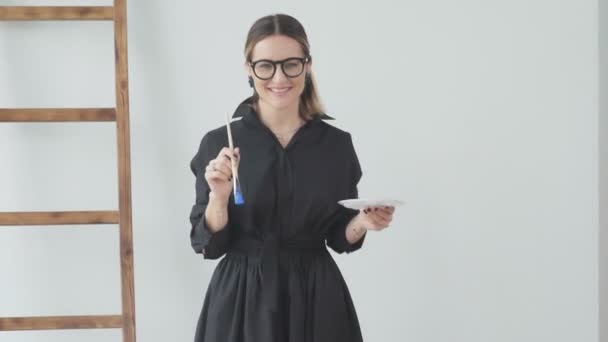 Kvinna med skarpa drag håller en borste för teckning och en palett — Stockvideo