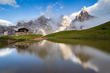 Arka plan üzerinde bir Alp dağ evi ile su yansıması Pale di San Martino tepeler (İtalyan Dolomites).