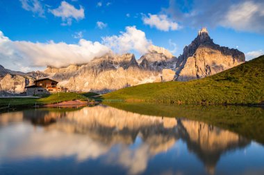 Gün batımında, arka planda bir Alp dağ evi ile suya yansıyan Pale di San Martino tepeler (İtalyan Dolomites).