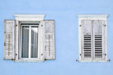 İki windows pancurlar mavi bir ev ile