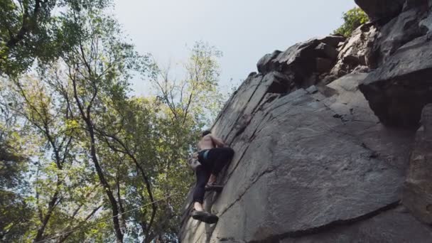 Topless climber abseiling cliff — Stockvideo