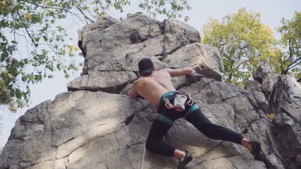 Gömleksiz genç adam kaya tırmanışı — Stok video