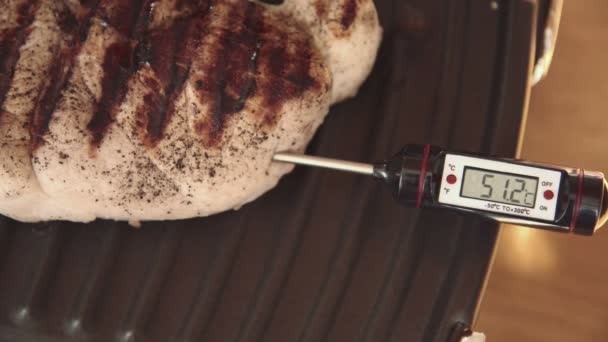 Мясной термометр в стейке помещен на электрический гриль — стоковое видео