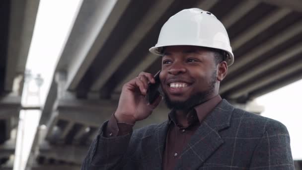 Усміхнений чоловік у білому жорсткому капелюсі по телефону — стокове відео