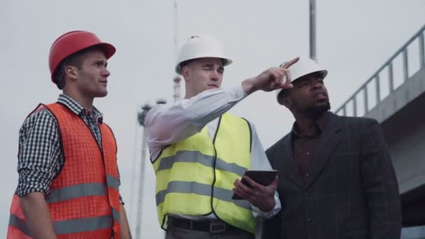 Workers in vests showing boss something on tablet — Αρχείο Βίντεο