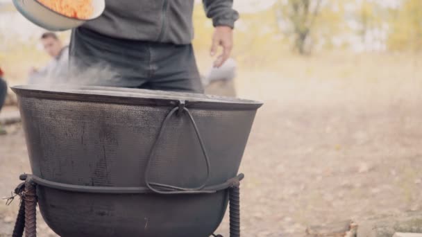 L'homme verse des carottes hachées dans un chaudron bouillant — Video