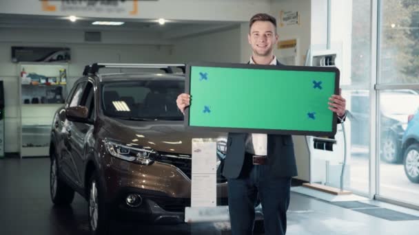 Man in Car Dealership Holding Green Sign — Stock Video