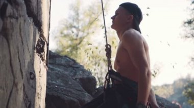 Güçlü üstsüz dağcı tebeşir ile ellerini ovuşturarak