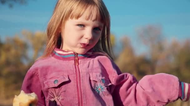 Маленька дівчинка їсть яблуко — стокове відео