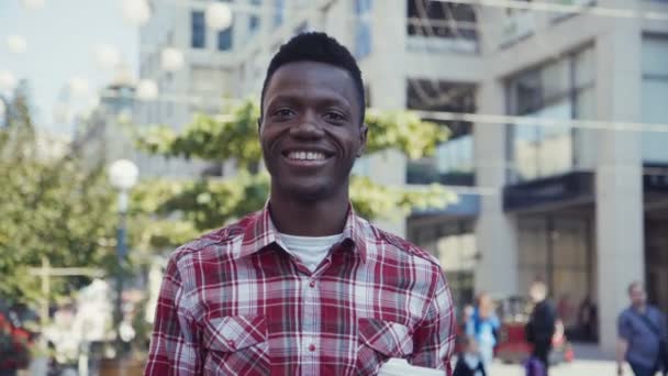 Homem afro-americano sorri e olha para a câmera — Vídeo de Stock