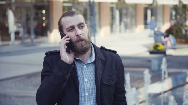 Knappe bebaarde man praten telefoon in stad — Stockvideo