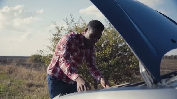 Hombre joven examinando el motor del coche . — Vídeos de Stock