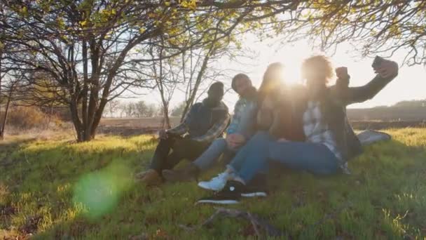 Fyra multiracial vänner sitter på landsbygden. — Stockvideo