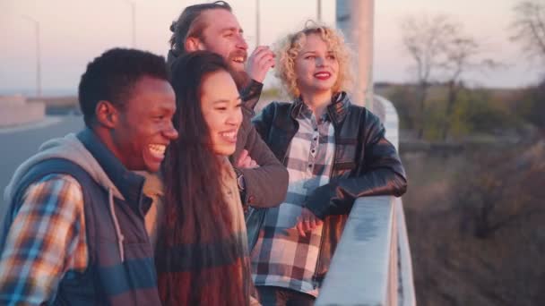 Four friends hanging out on bridge. — Stockvideo