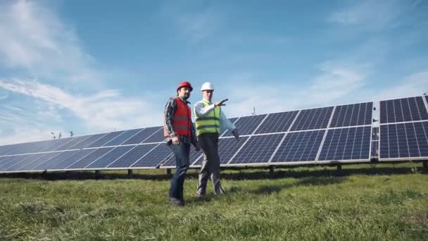 Рабочие, идущие между рядами солнечных батарей — стоковое видео