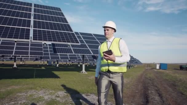 Férfi mellény gyaloglás közelében napelemek — Stock videók