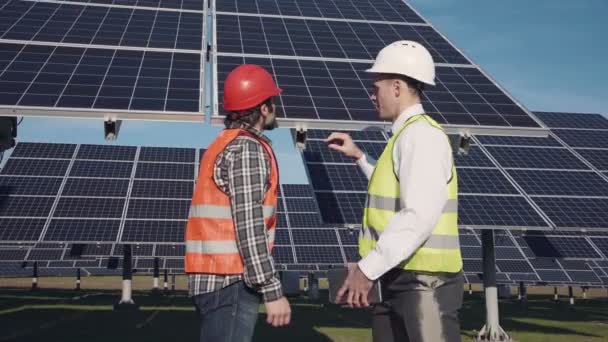技术人员讨论外的太阳能电池板阵列 — 图库视频影像