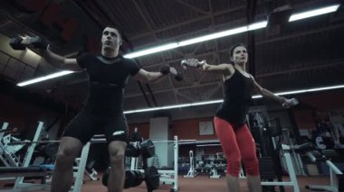 Kadın eğitmen ile spor salonunda ağırlık kaldırma