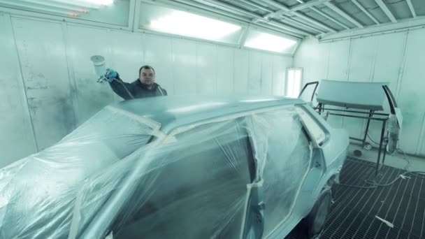 Mechanic spray painting a car in a body shop — Stock Video