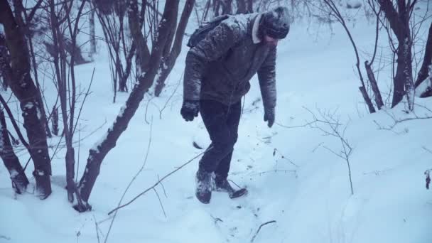 Man klättrar upp snöig backe — Stockvideo