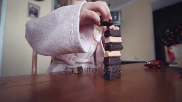 Маленькая девочка строит башню из конфет — стоковое видео