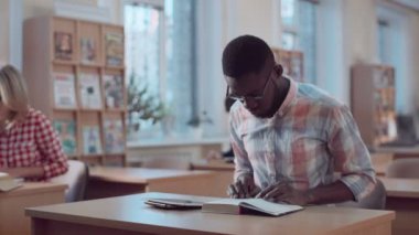Adam kitap ve kitaplıkta arıyor tablet