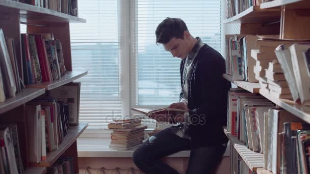 Nadenkende jongeman op zoek door middel van boeken — Stockvideo