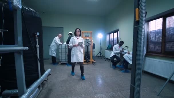Женщина-ученый проходит через лабораторию — стоковое видео