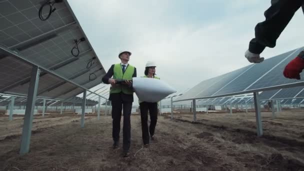 Trabajadores caminando en paneles solares y hablando — Vídeo de stock