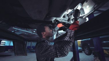 African mechanic working on the underside of a car clipart