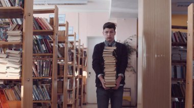 Yığın kitap ile şaşkın öğrenci