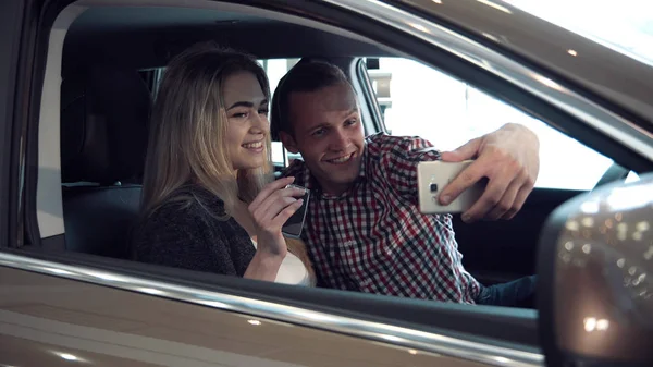 Excited young couple buying a new car and make selfie