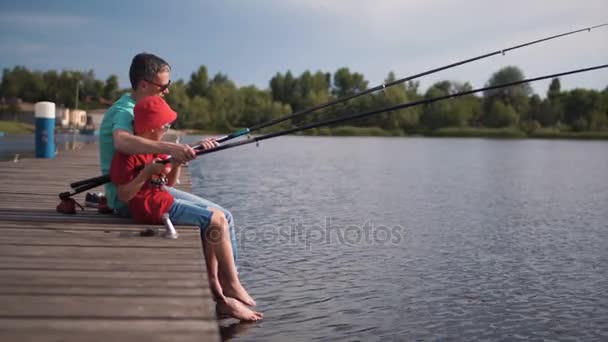 Мужчина и мальчик рыбачат на пирсе — стоковое видео