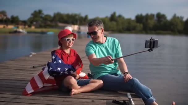 Far och son poserar med amerikanska flaggan — Stockvideo