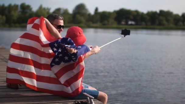Отец и сын позируют с американским флагом — стоковое видео